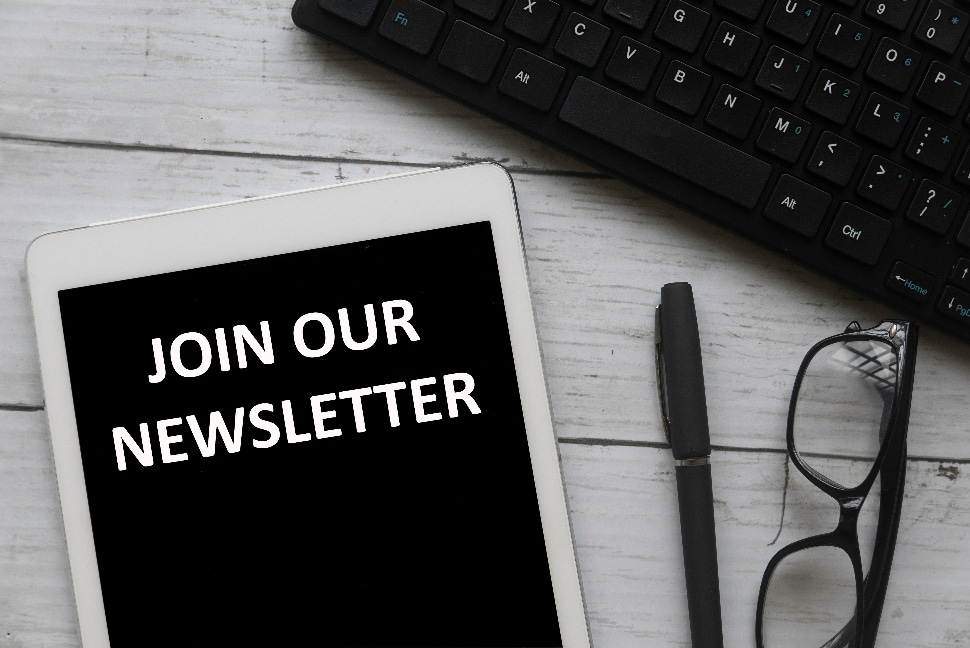 Tablet with the words 'join our newsletter' with glasses and computer