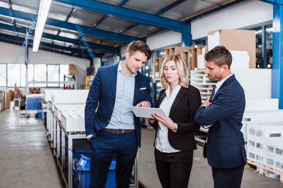 Two businessmen and a business woman looking at product launch plans in warehouse